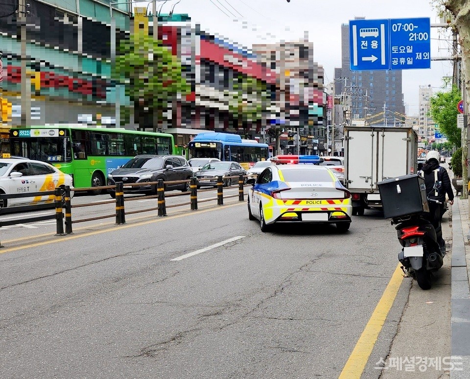 택배 차량이 서울 관악구 신림로 편도 2차선 가운데 한개 차로를 막았다. 경찰 2명이 단속하려고 내렸다가, 택배업의 어려운 점을 고려해 그냥 간다. 직무 유기일까? 배려일까? [사진=정수남 기자]