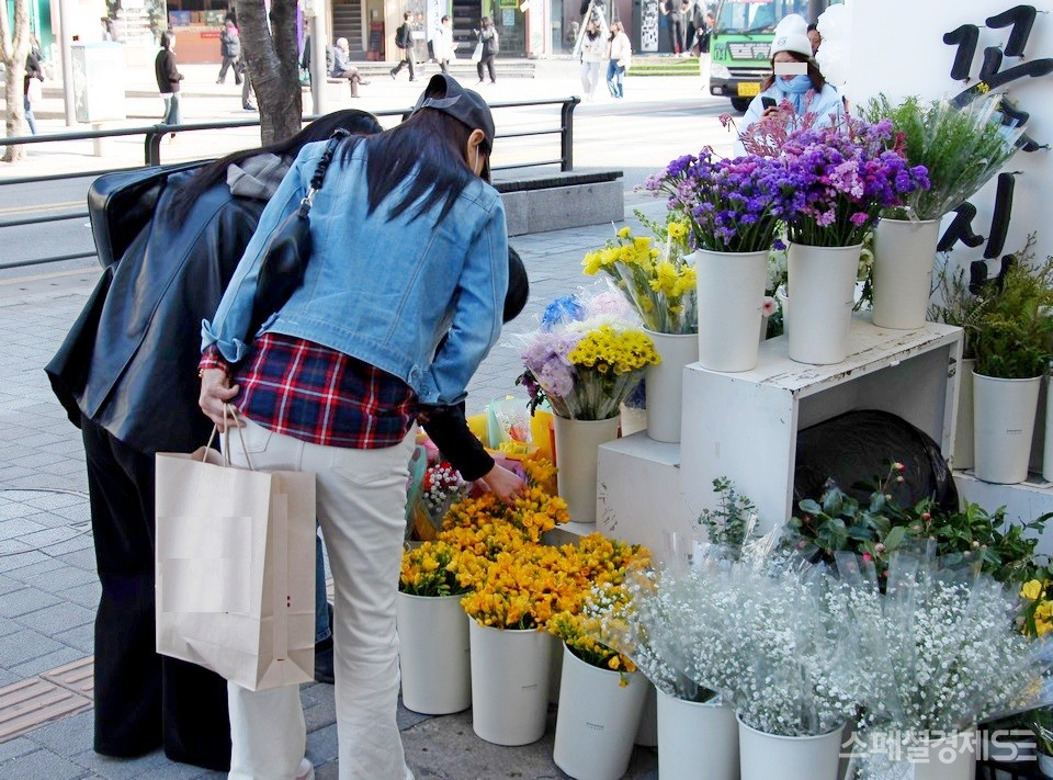 서울 서대문 신촌에 있는 꽃집. 꽃집 아가씨가 손님이 없자, 하릴없이 행인을 바라보고 있다. 그러다 20대 아가씨가 꽃을 사러 와 손을 재게 놀리고 있다. [사진=정수남 기자]